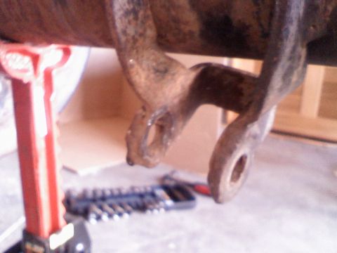 1996 Ford Bronco - Close-up of a rusted metal component, possibly from a vehicle's suspension or drivetrain, resting on a jack stand.