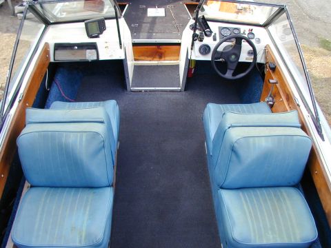 1968 Ford Mustang - The interior of a boat shows two rows of blue seats and a dashboard with a steering wheel.
