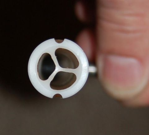 1994 Ford Bronco - A white plastic valve component with a three-pronged internal structure is held by a finger, with the Supermotors.net logo visible.