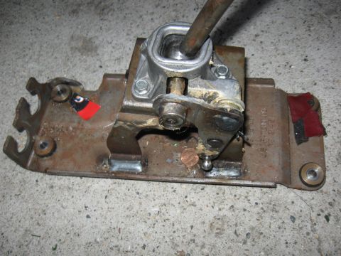 1989 Ford Taurus - Manual transmission shifter assembly with linkage and shift lever shown on a metal plate.