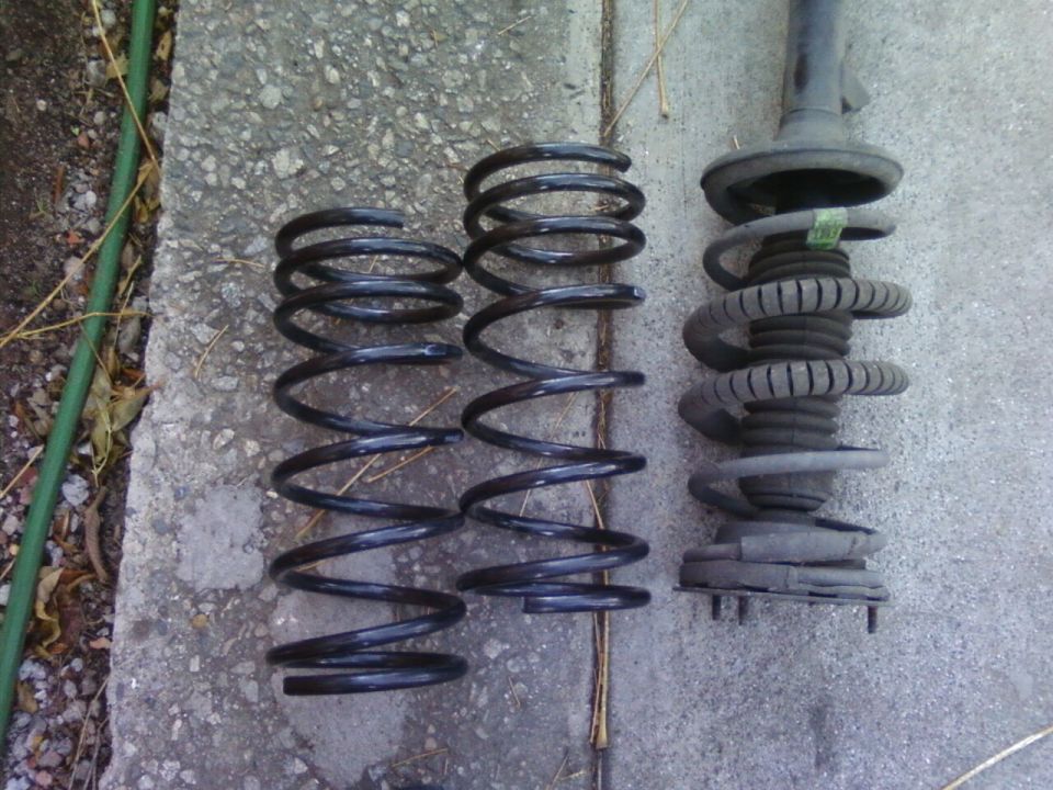 Three black coil springs and one shock absorber assembly on concrete