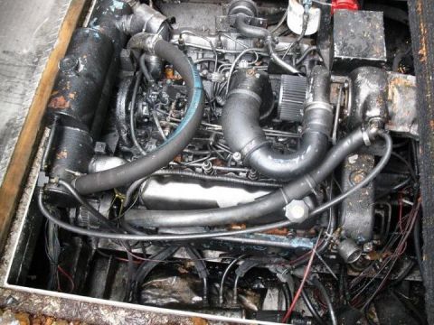 2000 Ford E350 - Engine compartment with oily diesel engine, black hoses, and wiring.