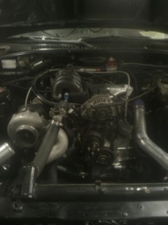 1987 Mazda RX-7 - Close-up of a modified engine bay a turbocharger and custom piping. Text from SuperMotors.net is visible.