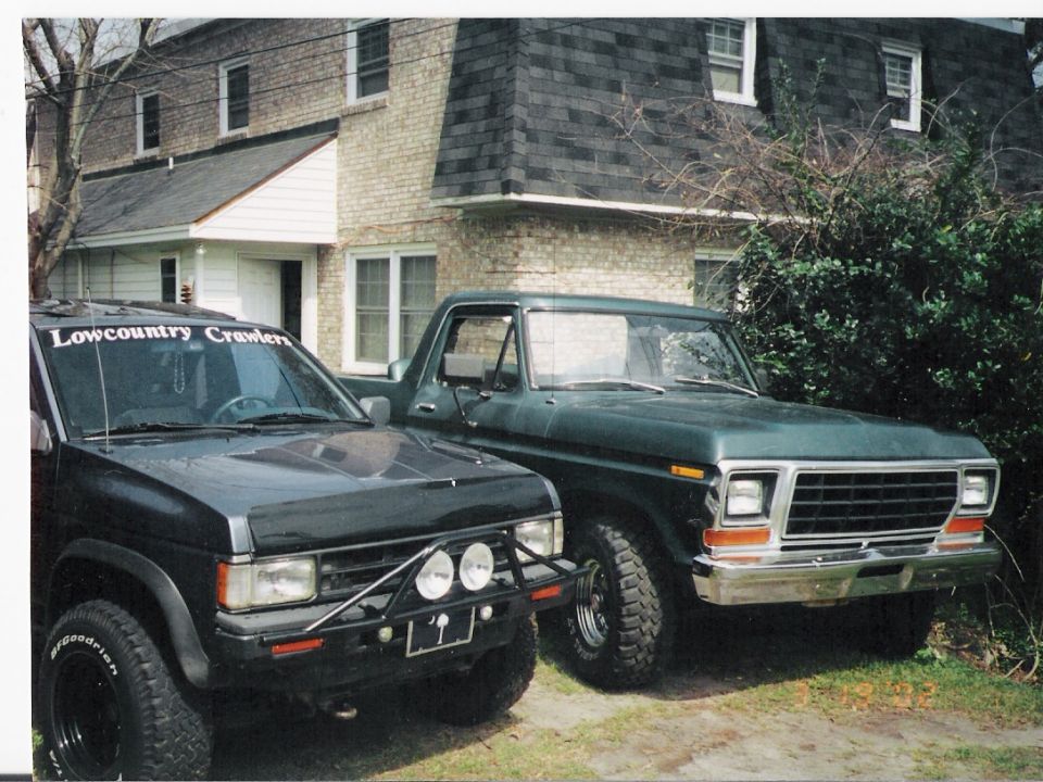 Green 1979 Ford Bronco front 3/4 view with black SUV