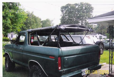 1979 Ford Bronco - This SUV has a roll cage and a fire extinguisher visible inside. Another vehicle is parked behind it.
