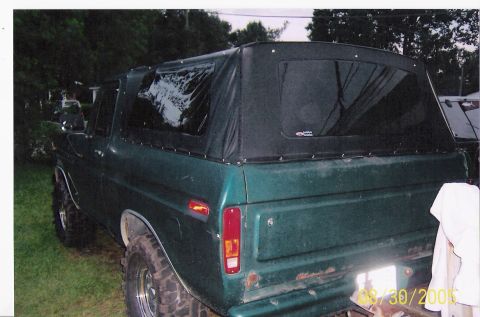 1979 Ford Bronco - Rear view of a green Ford Bronco with a black soft top and off-road tires.