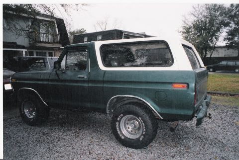 1979 Ford Bronco - Side profile of a green and white 1979 Ford Bronco parked on a gravel surface.