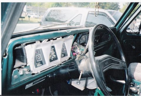1979 Ford Bronco - The dashboard of a vehicle is shown with the instrument cluster disassembled, revealing wiring and components.