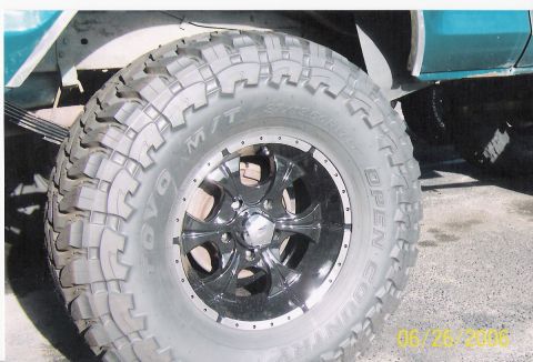 1979 Ford Bronco - A close-up view of a large off-road tire and custom wheel on a teal vehicle.