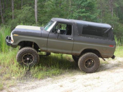 1979 Ford Bronco - This lifted 1978 Ford Bronco is shown from a three-quarter front angle on a dirt road surrounded by trees.