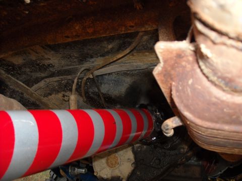 1979 Ford F-150 - Underside view of a driveshaft with reflective tape, connected to a rusty differential.