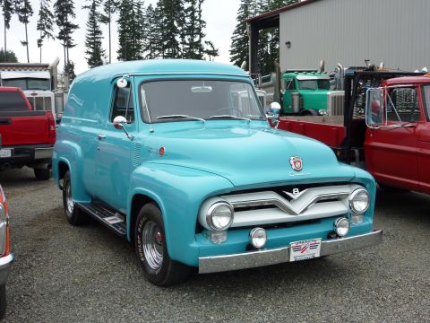 1981 Kenworth W900A - A turquoise 1955 Ford panel van is parked outdoors next to other trucks.