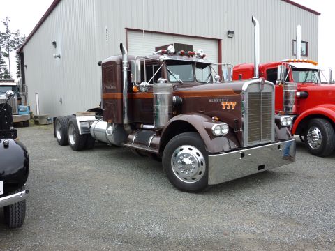 1981 Kenworth W900A - A classic Kenworth semi-truck with a brown and orange paint scheme is parked in front of a large building.