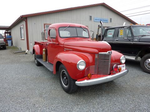 1981 Kenworth W900A - A red pickup truck is parked in front of a building with a sign that reads "John H. Keep Trucking".