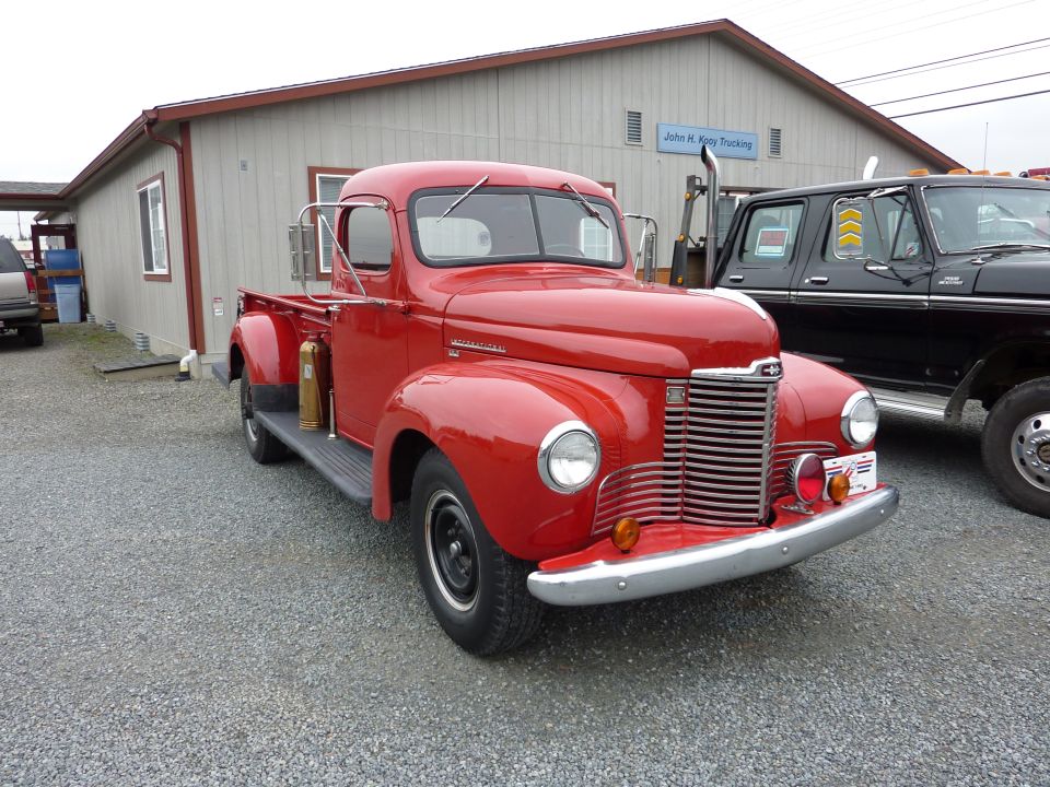 Red pickup truck with chrome grille and bumper, parked on gravel lot