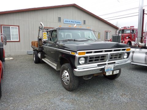 1981 Kenworth W900A - This black flatbed truck features a prominent chrome grille and dual rear wheels. The license plate is visible.