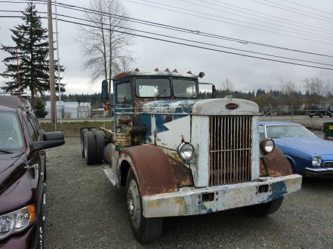 1981 Kenworth W900A - A weathered truck cab sits in a gravel lot under an overcast sky.