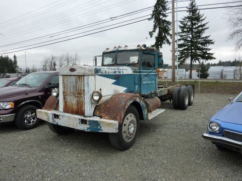 1981 Kenworth W900A - An old semi-truck chassis sits on a gravel lot, showing significant rust and wear.