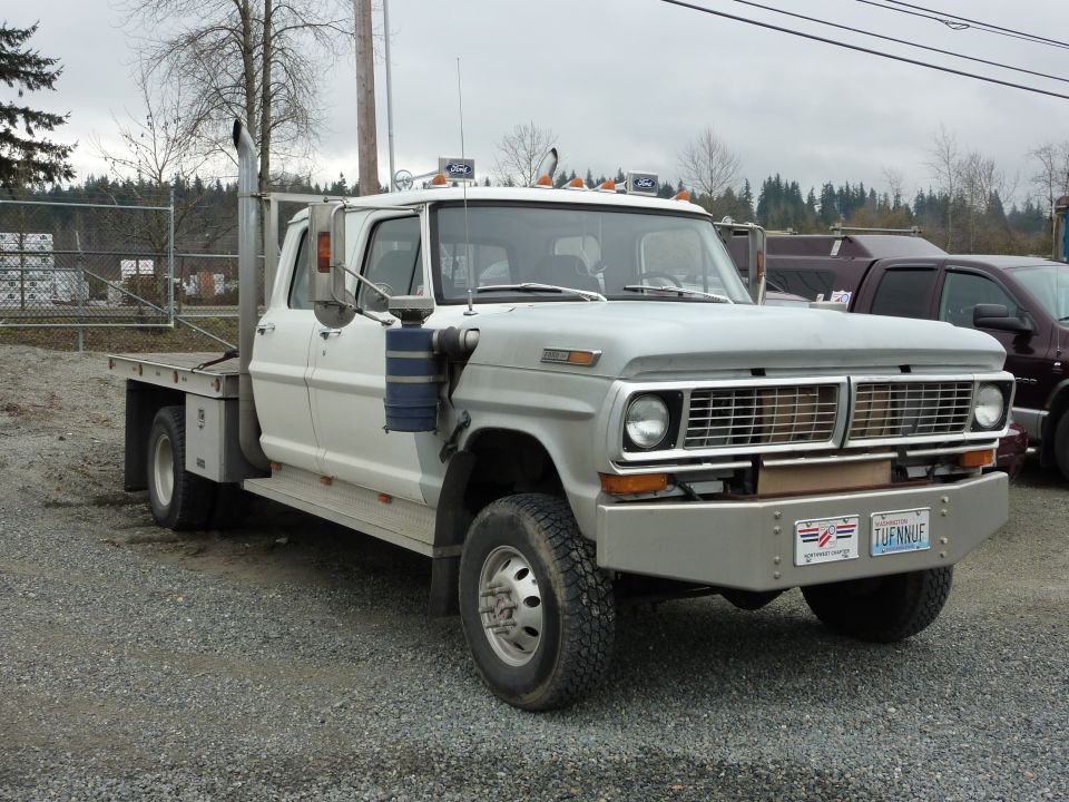 White flatbed truck with dual rear wheels, chrome bumper, and vertical exhaust stacks