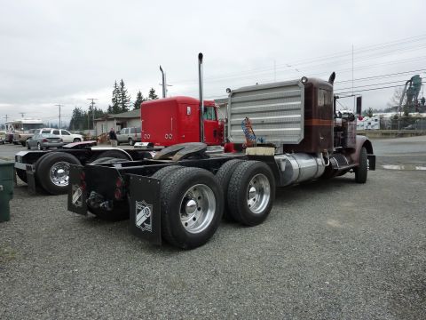 1981 Kenworth W900A - A brown semi-truck cab and chassis is parked outdoors, showing its rear wheels and chrome exhaust stacks.