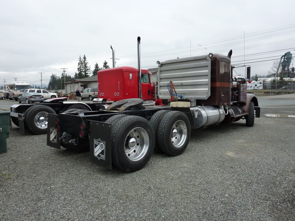 Brown semi-truck cab and chassis rear view with chrome stacks and dual rear wheels