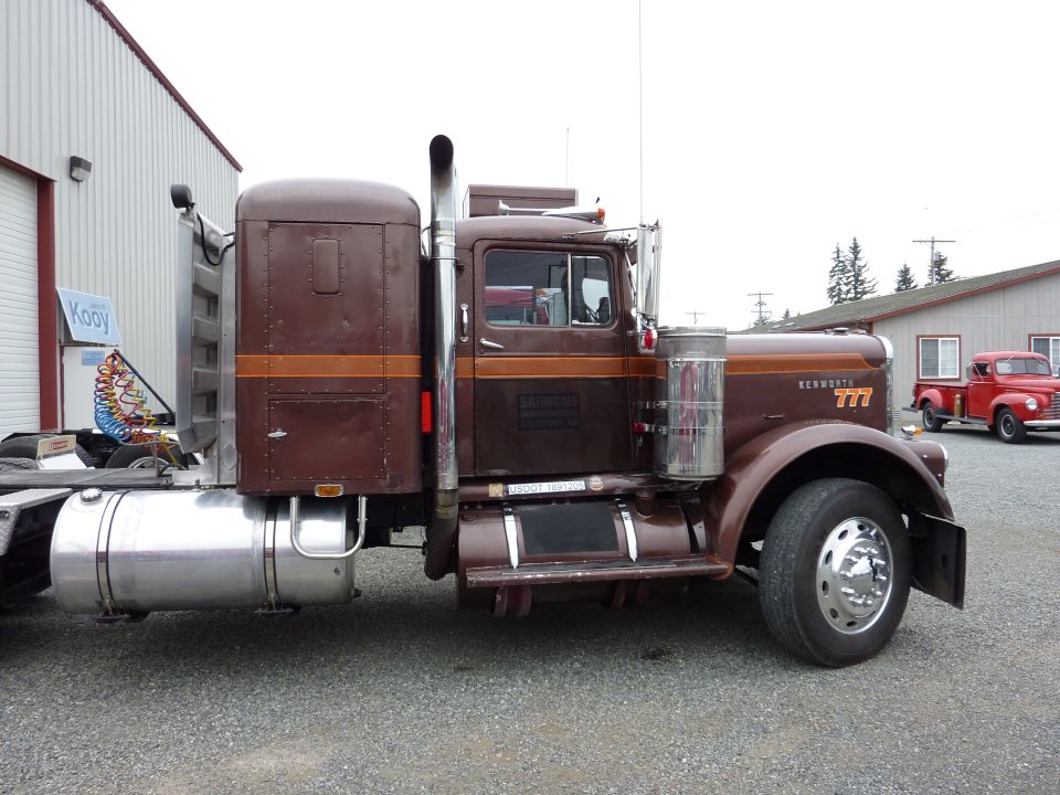 Side view of brown Kenworth conventional tractor with sleeper box and chrome stack