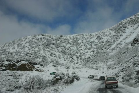 1991 Ford Bronco - A 1991 Ford Bronco travels down a snow-covered mountain road under a cloudy sky.