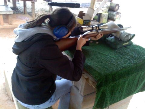 2001 Ford F-150 - A woman wearing ear protection takes aim with a rifle at a shooting range.