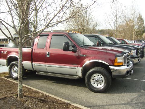 2007 Ford Mustang - A row of pickup trucks are parked in a lot, with a red and silver Ford F-350 in the foreground.