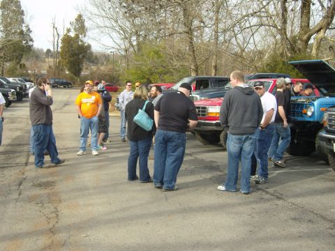 2007 Ford Mustang - A group of people are looking at trucks in a parking lot, with one truck's hood up.
