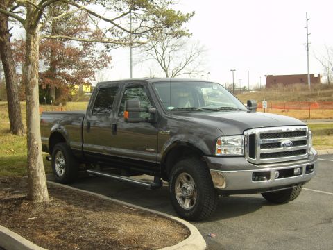 2007 Ford Mustang - This Ford F-250 Super Duty truck is parked in a lot with trees and a fence in the background.