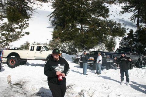 1991 Ford Bronco - Several modified Ford trucks are parked in a snowy landscape, with people standing around them.