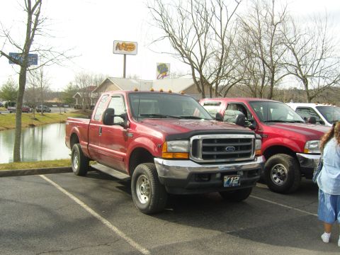 2007 Ford Mustang - A red Ford F-Series truck is parked in a lot next to other vehicles, with a Bass Pro Shops sign in the background.