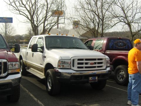 2007 Ford Mustang - A white Ford F-250 Super Duty truck is parked next to another truck, with a person standing nearby.