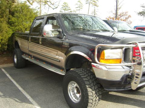 2007 Ford Mustang - A lifted Ford F-350 Super Duty pickup truck is parked outdoors next to another vehicle.
