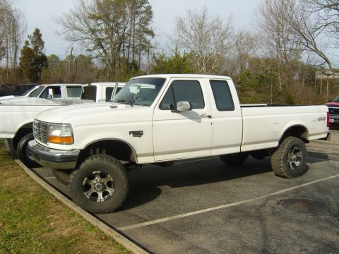 2007 Ford Mustang - A white pickup truck is parked in a lot next to other vehicles.
