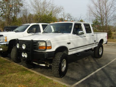 2007 Ford Mustang - Lifted white Ford F-250 Super Duty truck parked in a lot with another truck beside it.