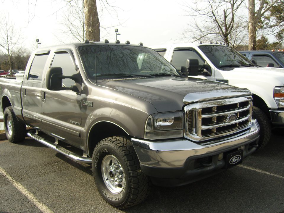 Gray Ford F-250 Super Duty pickup truck parked next to a white truck