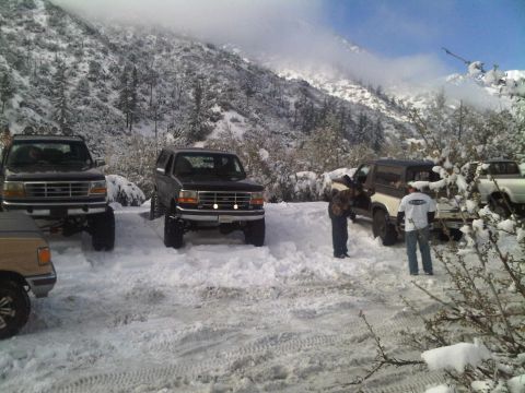 1986 Ford Bronco - Several modified SUVs are parked in a snowy mountain landscape.