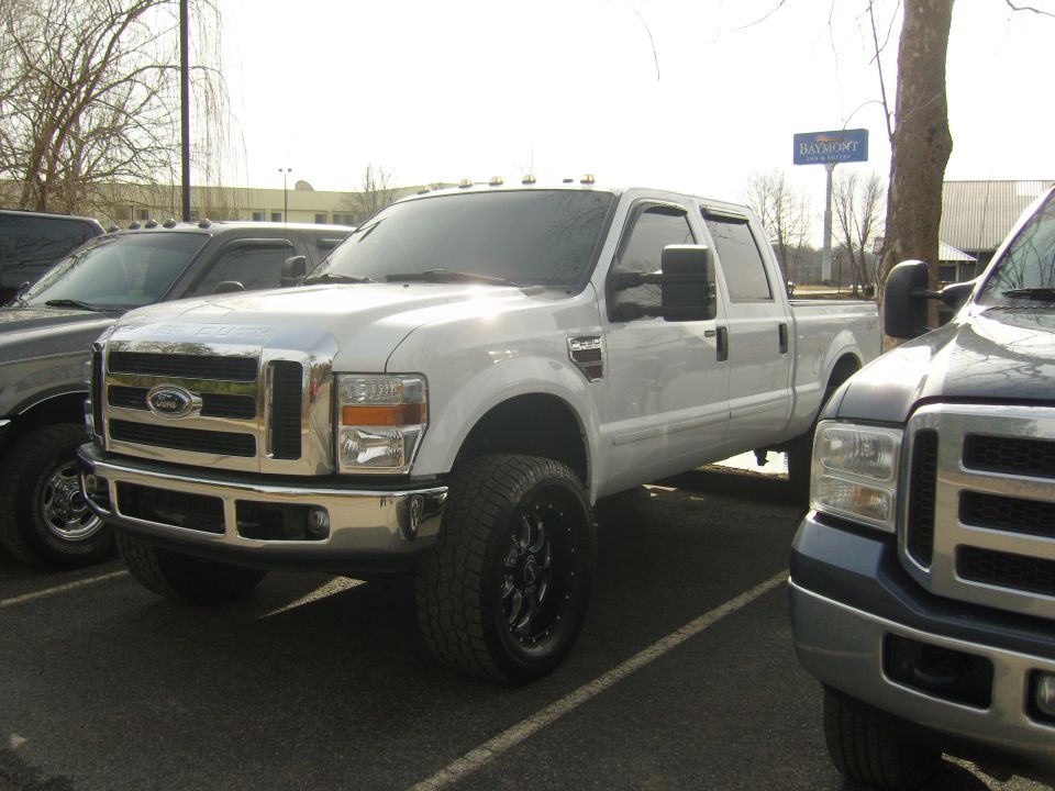 White Ford F-Series truck with chrome grille and black rims, parked in a lot