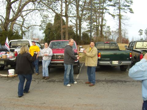 2007 Ford Mustang - People gather around a red pickup truck in a parking lot.