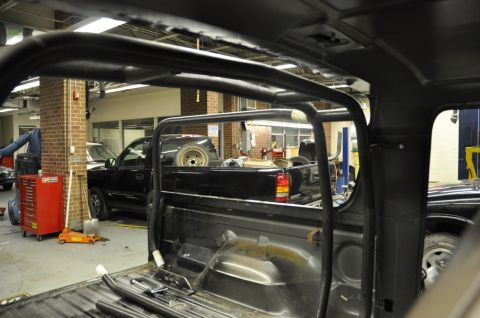 1996 Ford Bronco - The interior of a black pickup truck shows a prominent roll cage, with another black truck visible through the windows.