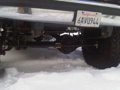 1986 Ford Bronco - A view of the rear axle and suspension of a vehicle, with a California license plate visible, parked in the snow.
