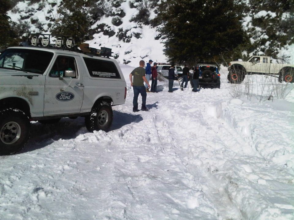 White Ford Bronco with off-road tires and roof lights in snow