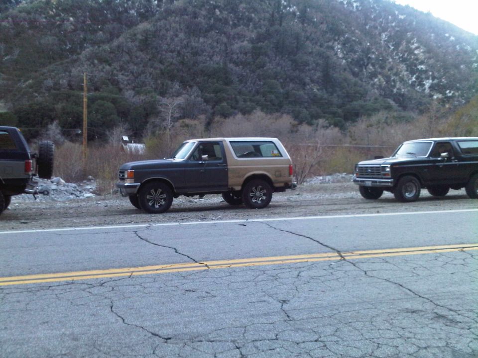 Two-tone Ford Bronco parked on roadside with a black Bronco behind it