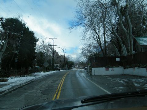 1982 Ford Bronco - A wet road winds through a snowy landscape with power lines and trees.
