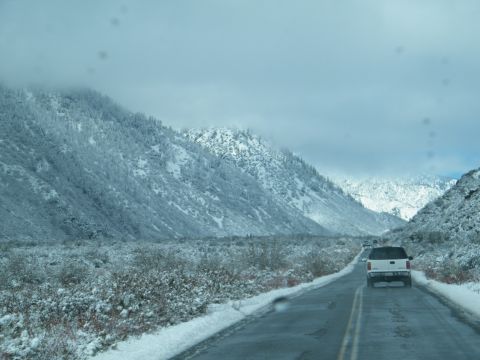 1982 Ford Bronco - A snowy mountain pass road with several vehicles driving through the winter landscape.