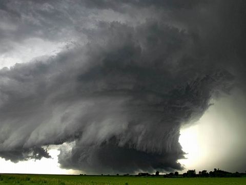 1991 Ford Bronco - A massive, dark supercell thunderstorm looms over a green field under a bright sky.