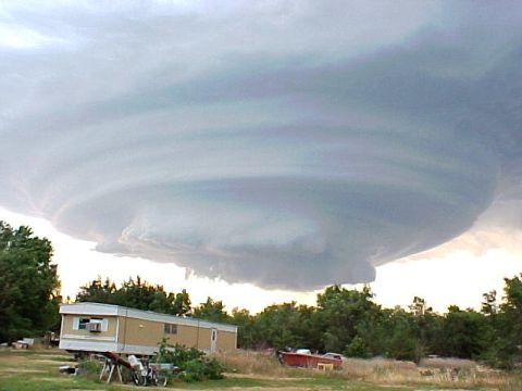 1991 Ford Bronco - A dramatic storm cloud formation looms over a trailer home and surrounding trees.