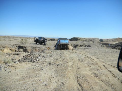 1997 Ford Ranger - Two vehicles appear stuck in a challenging off-road environment under a clear blue sky.
